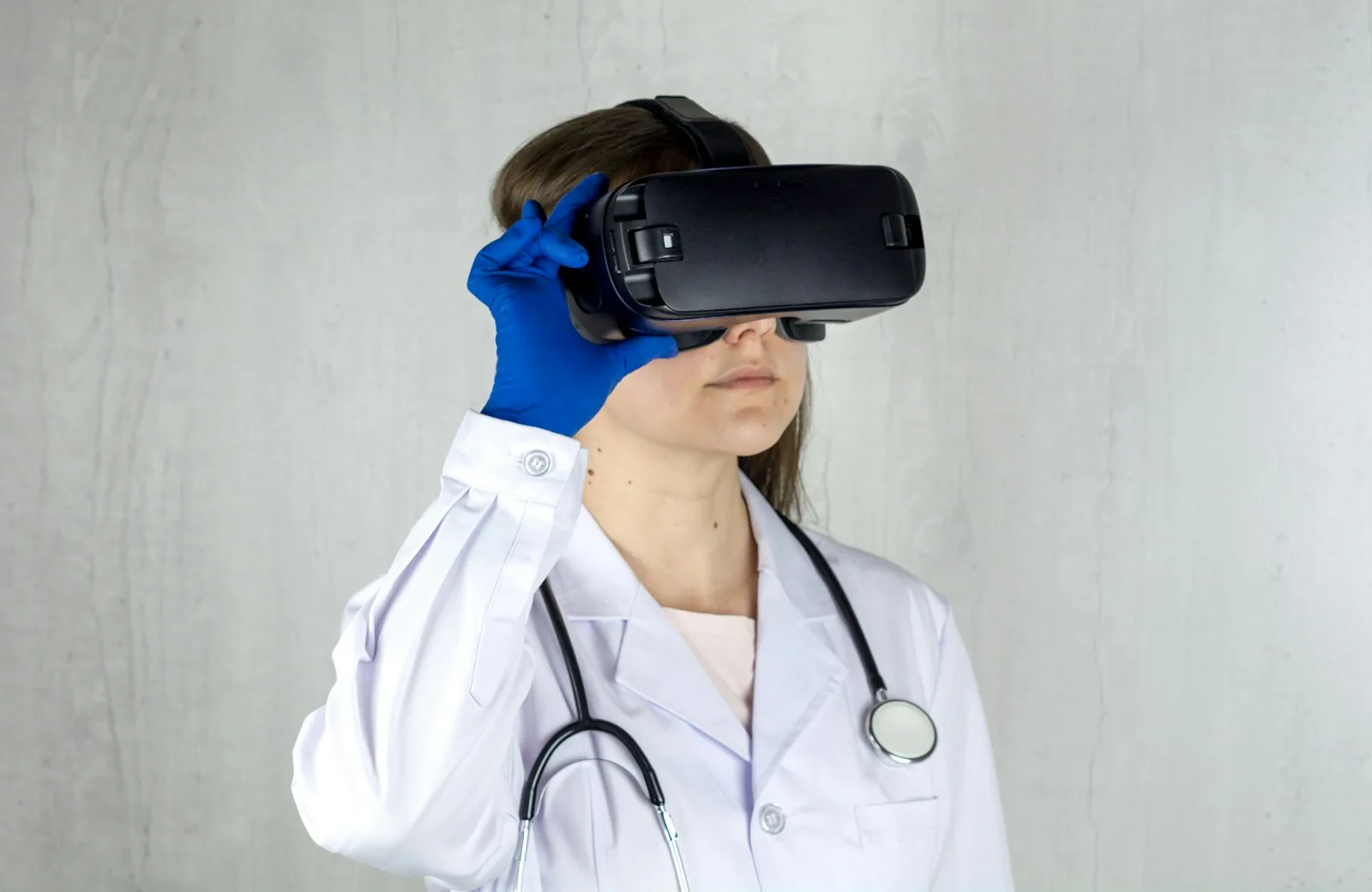 A clinician in a white coat and blue gloves wearing a virtual reality headset