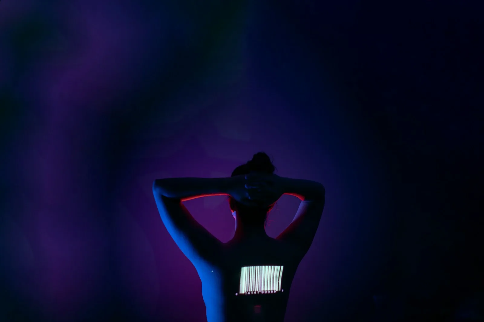 Dancer silhouetted against neon stage lighting, arms raised